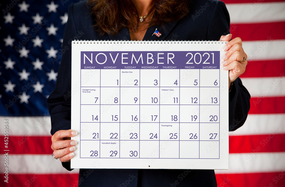Unface lady holding a November 2021 Calendar in front of a United States' flag.