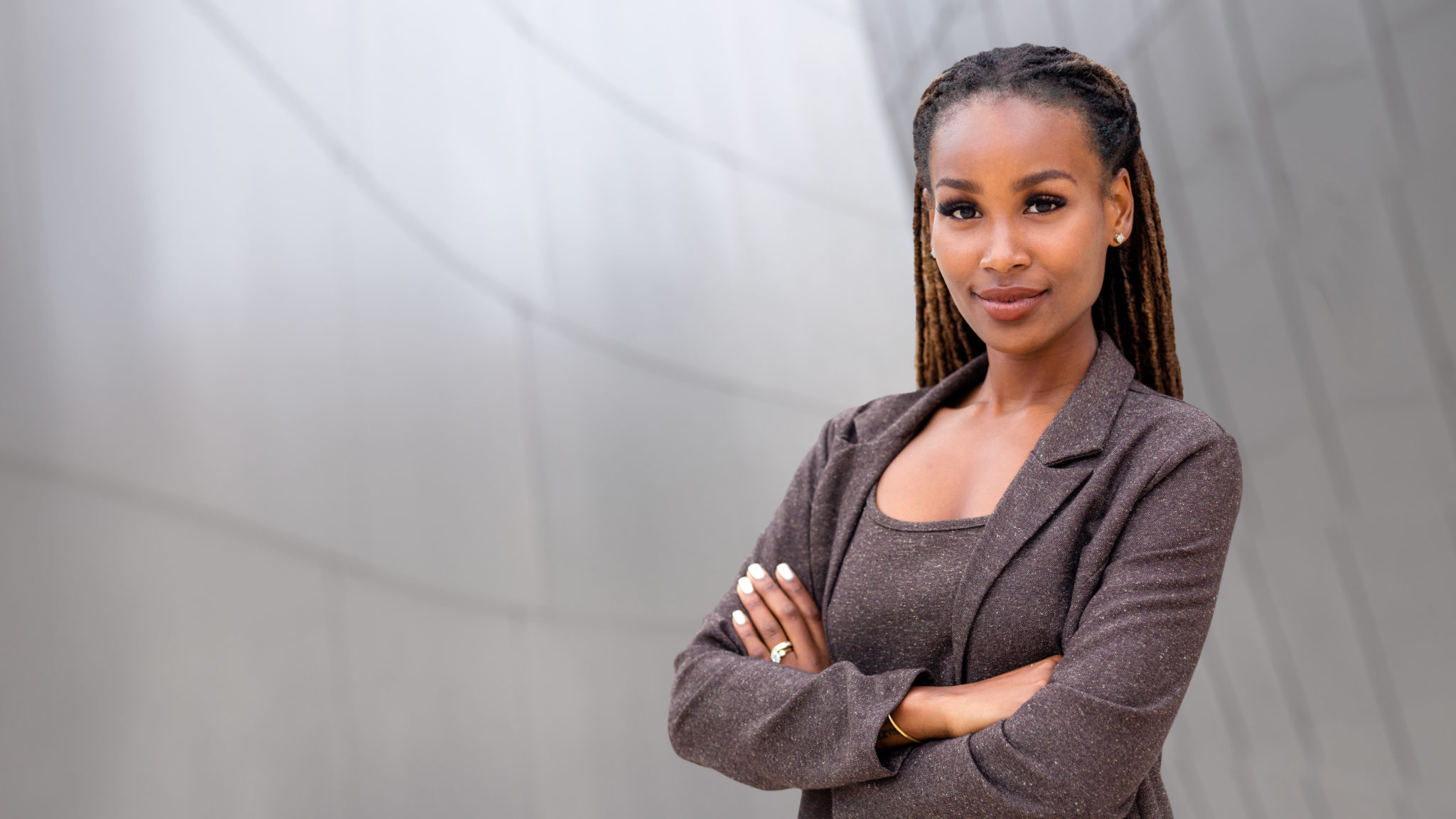 Black woman Governor crossing her arms in front of a building.