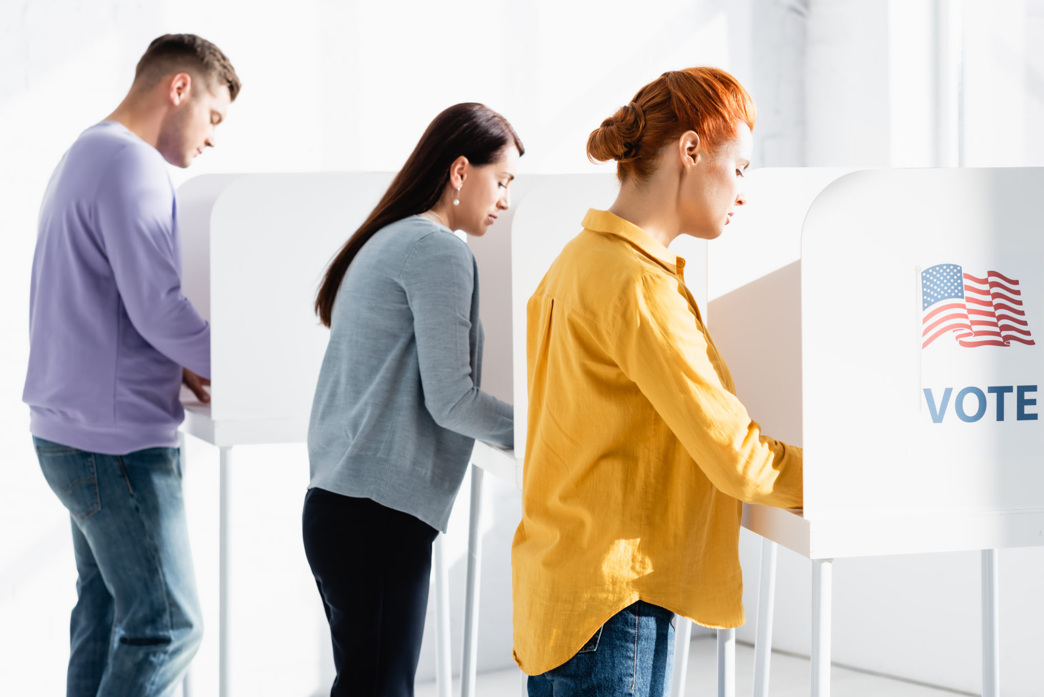voters in polling booths with american flag and vote lettering on blurred background